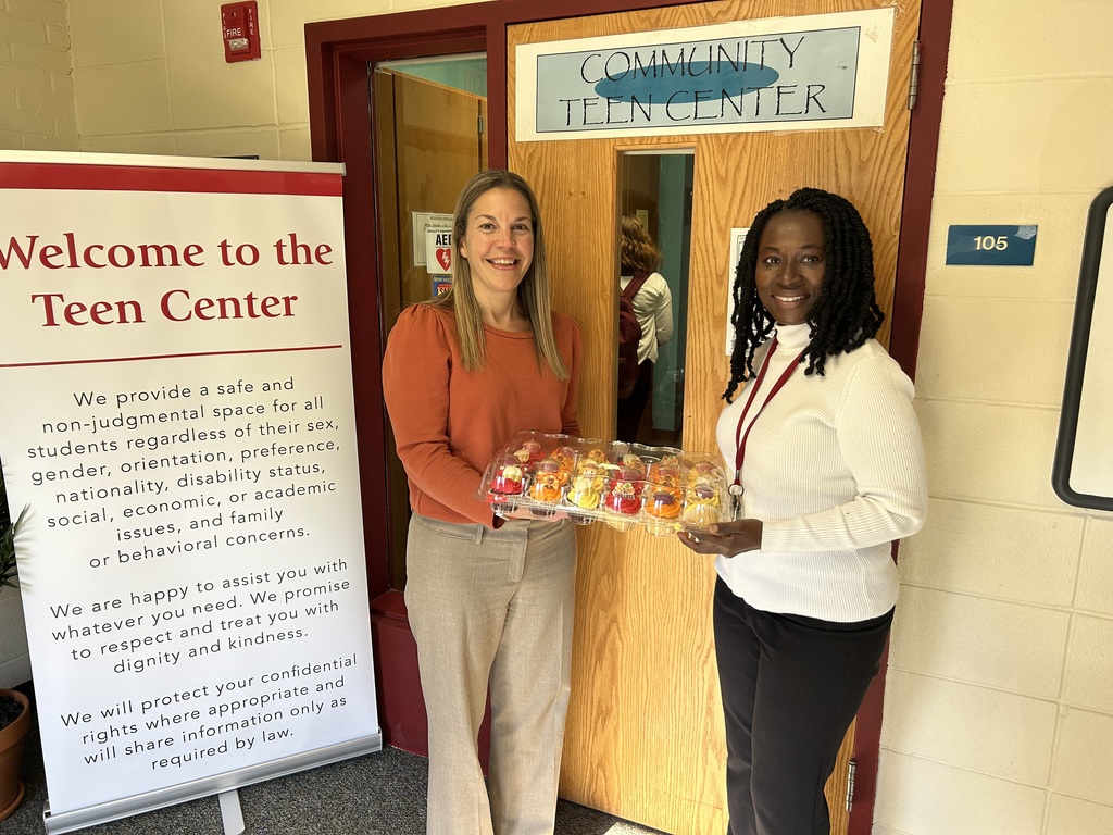 Dr. Nicosia and Ms. Asamoah standing in front of the Teen Center holding a container of cupcakes.